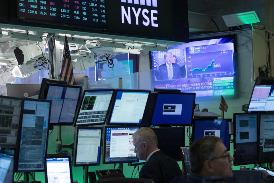 Traders at the New York Stock Exchange listen to President Donald Trump's televised White House news conference, Tuesday, March 17, 2020 in New York. Stocks are adding sharply to their gains on Wall Street after the president and his team announced more measures to combat the coronavirus outbreak. (AP Photo/Mark Lennihan)