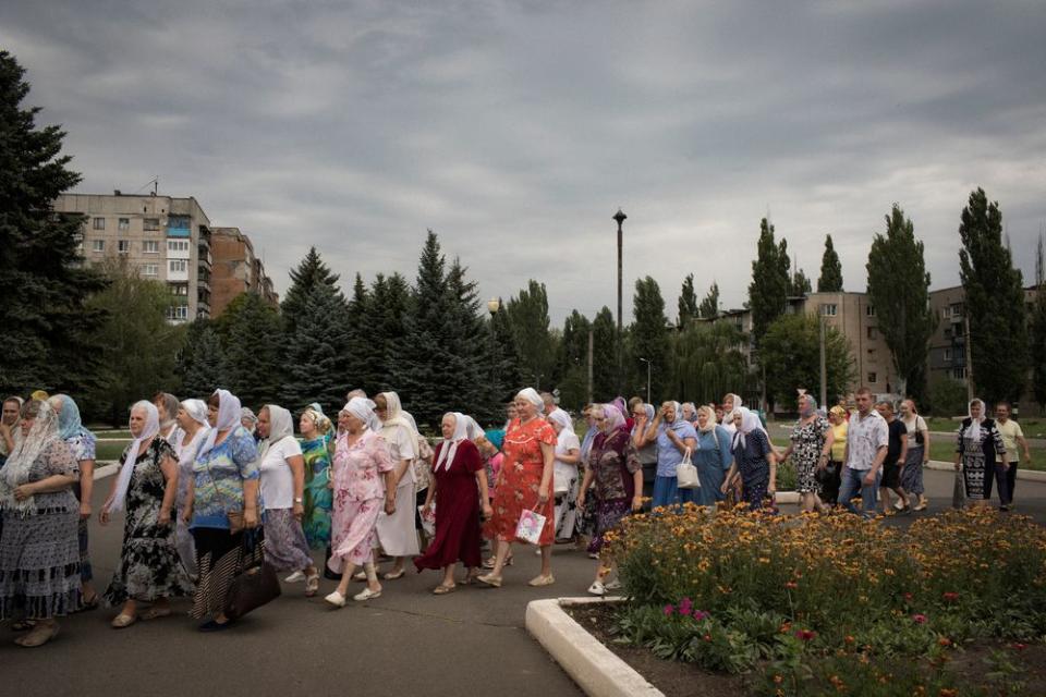 Parishioners participate in a procession in front of the Church of St. Mary Magdalene in Avdeevka. The church stands next to a minefield.