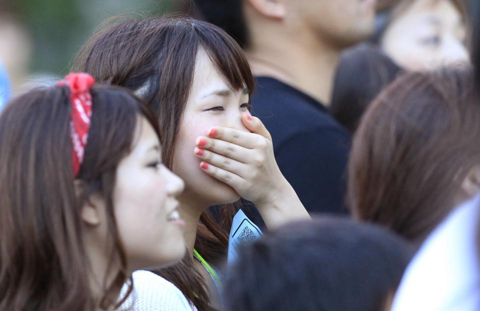 In this photo taken Monday, Aug 5, 2013, a woman is brought to tears listening to Chris Hart sing at an outdoor concert in Tokyo. Hart is a San Francisco-born singer who gained fame in Japan through his heartfelt J-pop covers. His album of cover versions of Japanese pop tunes is rising on the charts. And the crooner, a past winner of the Japanese karaoke show "Nodojiman The! World," is scoring on this nation's equivalent of “American Idol,” being billed as a genius who understands the “soul” of Japan. (APphoto/Azusa Uchikura)