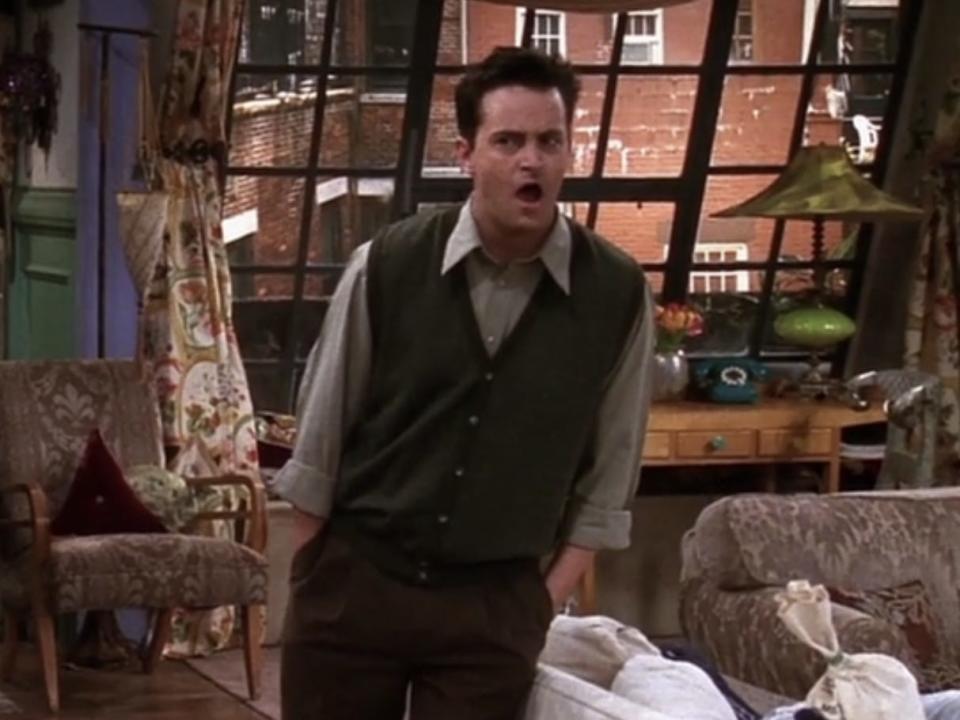chandler bing in a green button down, green sweater vest, and rust colored slacks