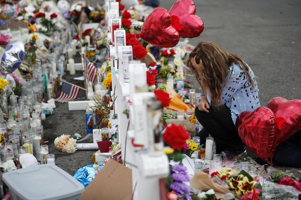 Gloria Garces kneels in front of crosses at a makeshift memorial near the scene of a mass shooting at a shopping complex Tuesday, Aug. 6, 2019, in El Paso, Texas. The border city jolted by a weekend massacre at a Walmart absorbed more grief Monday as the death toll climbed and prepared for a visit from President Donald Trump over anger from El Paso residents and local Democratic leaders who say he isn't welcome and should stay away. (AP Photo/John Locher)