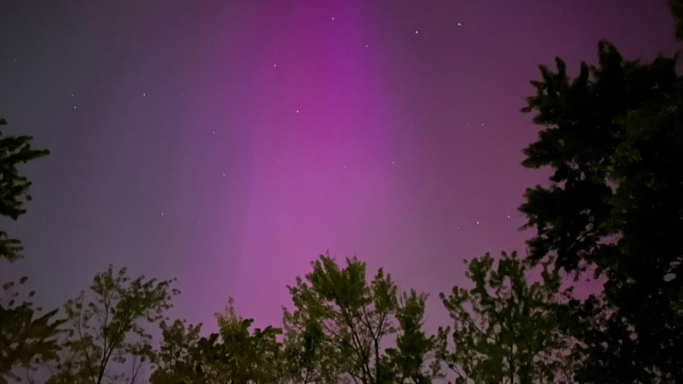 View of purplish northern lights and the Big Dipper in dark night sky