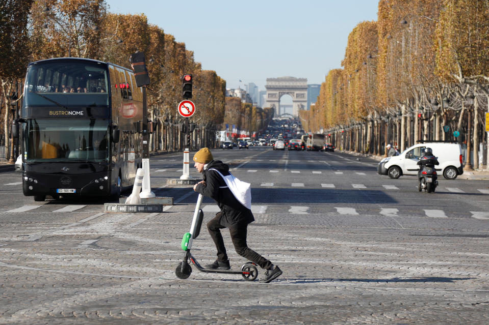 A man passes by the Champs Elysees avenue as he rides a dock-free electric scooter Lime-S by California-based bicycle and scooter sharing service Lime, in Paris, France, November 9, 2018. REUTERS/Charles Platiau