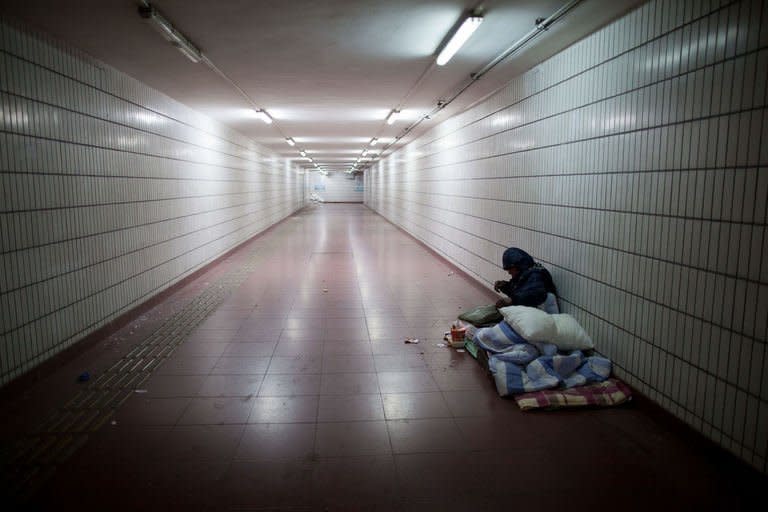 A homeless man lies on his bed in an underpass in Beijing on December 7, 2012. China's stated aim to narrow the income gulf between its sports-car driving elite and vast numbers who still live in poverty will need radical political and economic changes to work, say economists