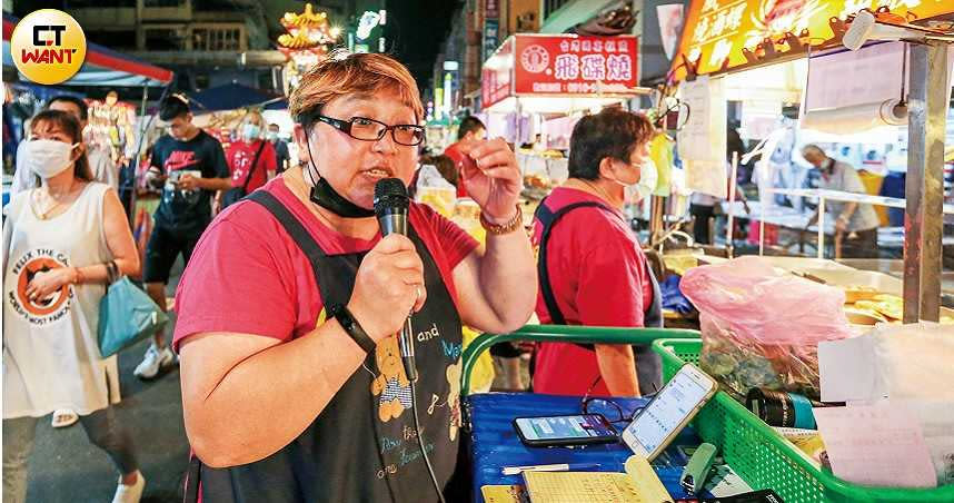 艋舺夜市商圈發展促進會會長陳姿卉用自己的手機號碼當聯絡窗口，幫攤商代接外送訂單後，就用麥克風指揮攤商備餐。（圖／鄭清元攝）