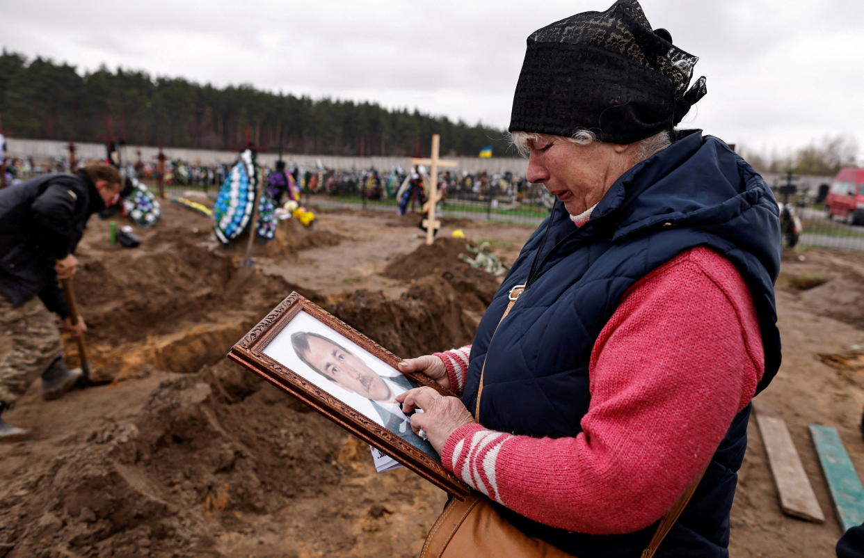 Natalia Maznichenko, 57, holds a photograph of her husband Vasyl Maznichenko, 61, who according to her was killed during Russian shelling on their building, as she mourns him during his funeral, amid Russia's invasion of Ukraine, at the cemetery in Bucha, Kyiv region, Ukraine April 21, 2022. REUTERS/Zohra Bensemra     TPX IMAGES OF THE DAY