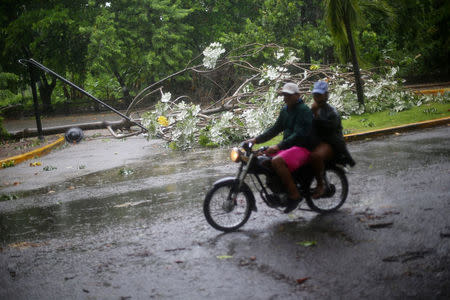 People ride past a fallen tree and lamp post as Hurricane Irma moves off the northern coast of the Dominican Republic, in Puerto Plata, Dominican Republic September 7, 2017. REUTERS/Ivan Alvarado