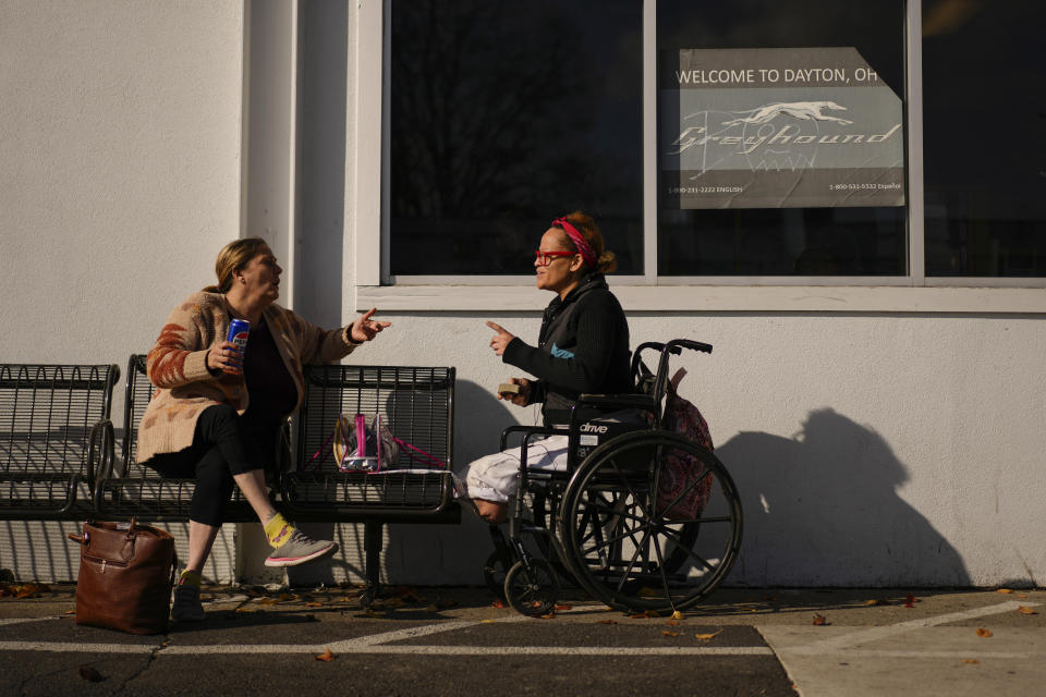 Tina Fontaine, left, and Tina Green talk as they wait for a bus outside the entrance to the Greyhound's Dayton Trotwood Bus Station in Dayton, Ohio, Wednesday, Nov. 22, 2023. Green is en route to St. Louis. Despite inflation and memories of past holiday travel meltdowns, millions of people are expected to hit airports and highways in record numbers over the Thanksgiving Day break. (AP Photo/Carolyn Kaster)