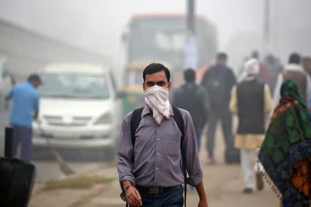 A man covers his face with a handkerchief during heavy fog in Delhi, India December 1, 2016. REUTERS/Cathal McNaughton