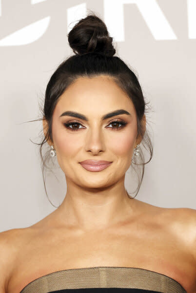 Paige DeSorbo poses in front of a step and repeat wearing a gown.