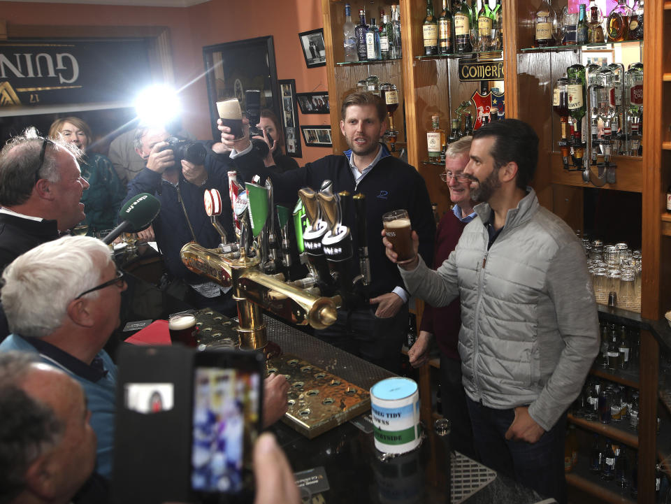 President Trump's sons Eric and Donald Jr., right, pour a pint for locals at a pub in Doonbeg west of Ireland Wednesday, June 5, 2019. President Trump is overnighting in Ireland before attending 75th anniversary of the D-Day landings events in northern France Thursday. (AP Photo/Peter Morrison)