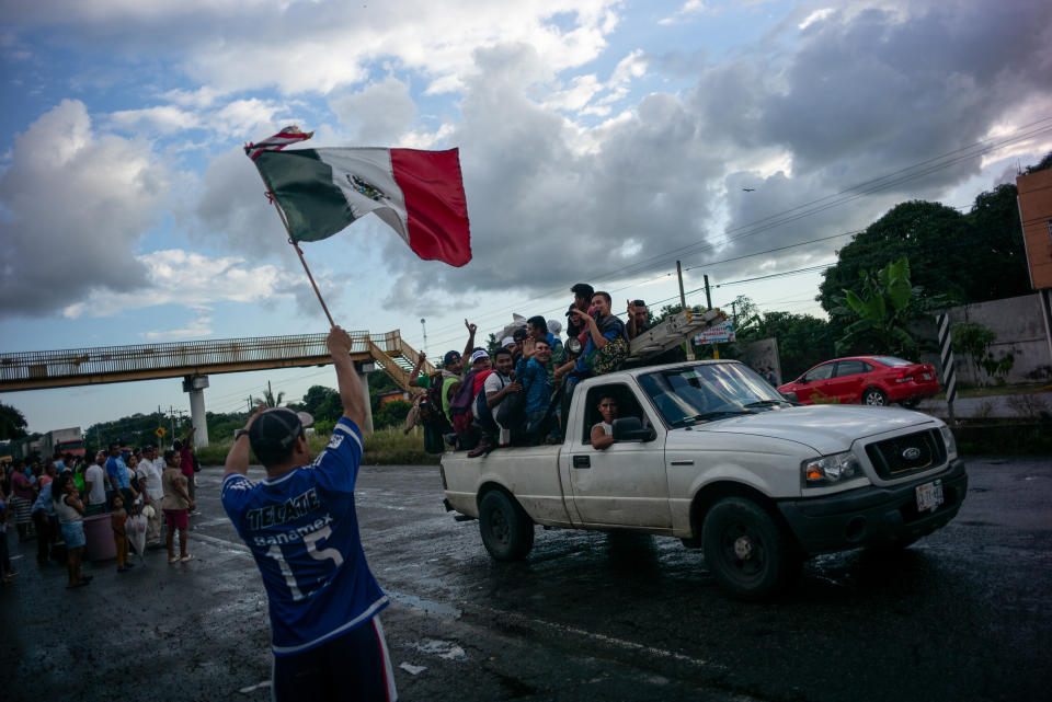 A man waves a flag as he greets a group of Central American refugees and asylum-seekers in the town of Huixtla, Chiapas state, Mexico, on Monday. As thousands of migrants continued a march from Central America toward the U.S. border, President Trump said the U.S. will cut off foreign aid to Guatemala, Honduras and El Salvador. (Photo: Alejandro Cegarra/Bloomberg via Getty Images)