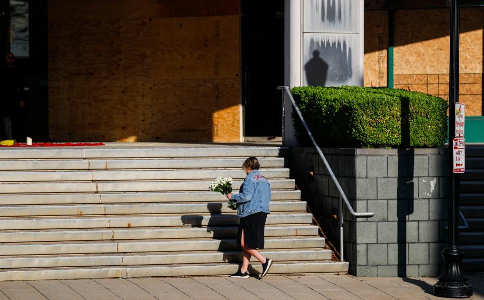 A woman brings five bouquet of flowers to the steps of Old National Bank on April 11, 2023, in Louisville, Ky., a day after a gunman killed five people.