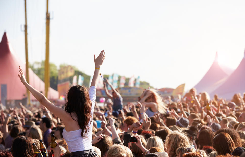 Crowd of people enjoying themselves at outdoor music festival.