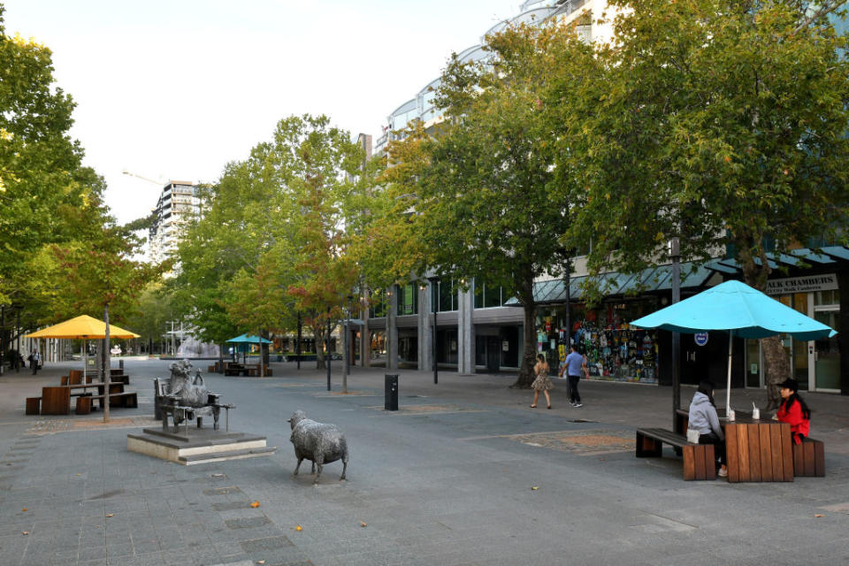 People sit at a table in a near empty street in Canberra's Civic last month. Source: Getty