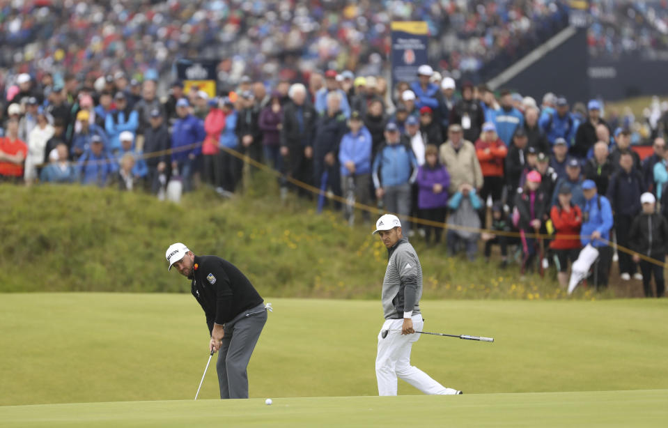Northern Ireland's Graeme McDowell, left putts on the 14th green watched by Xander Schauffele of the United States during the first round of the British Open Golf Championships at Royal Portrush in Northern Ireland, Thursday, July 18, 2019.(AP Photo/Peter Morrison)