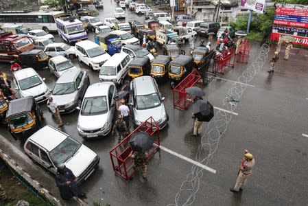 Indian security personnel stand guard as they stop traffic during restrictions in Jammu