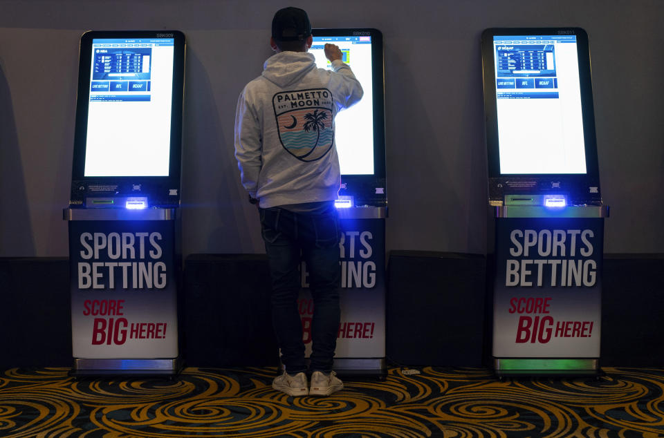 A man navigates a sports betting kiosk at Turfway Park Racing & Gaming, Friday, Dec. 22, 2023, in Florence, Ky. Sports betting has spread rapidly across U.S. states in the past five years. But the odds for further expansion may be fading as state legislatures prepare to return to work in 2024. (AP Photo/Carolyn Kaster)