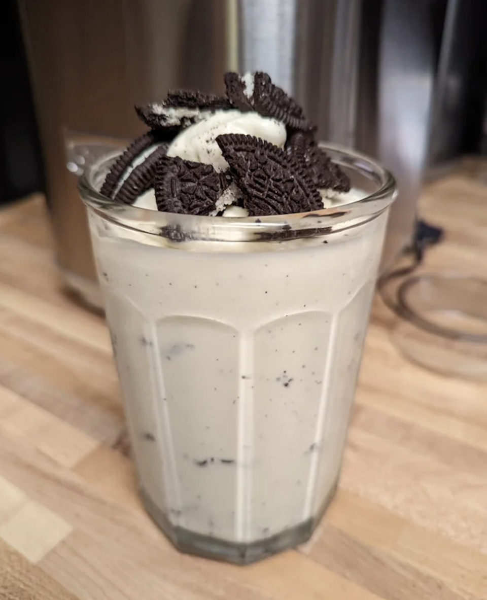 A milkshake with crushed cookies on top, served in a tall glass