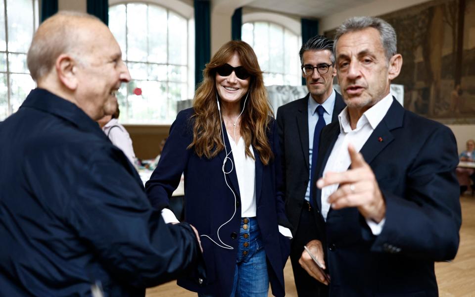 Carla Bruni and Nicolas Sarkozy chat with a local after voting at a polling station in Paris