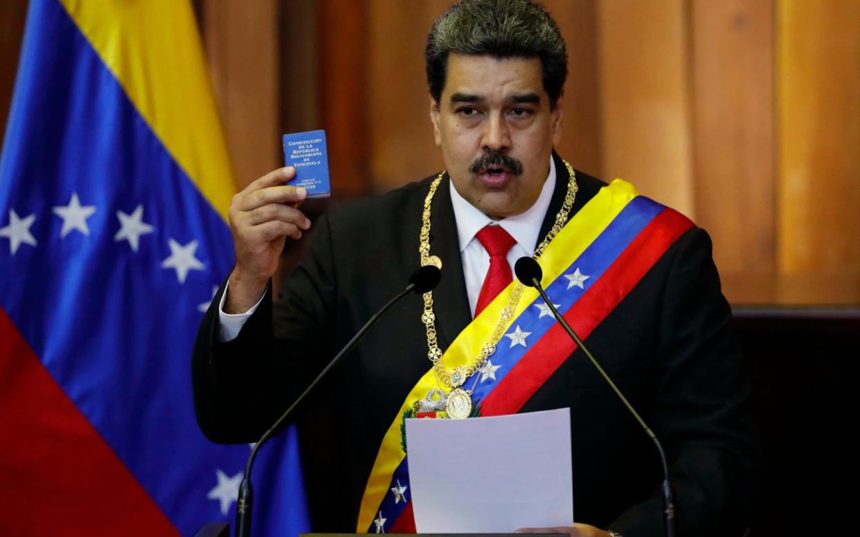 Venezuela's President Nicolas Maduro holds up a small copy of the constitution as he speaks during his swearing-in ceremony at the Supreme Court in Caracas - AP