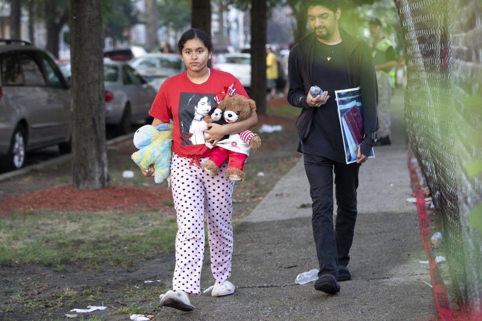 People carry things away from the scene of a fire that killed several people including multiple children Sunday, Aug. 26, 2018, in Chicago. The cause of the blaze hasn't been determined. (Erin Hooley/Chicago Tribune via AP)