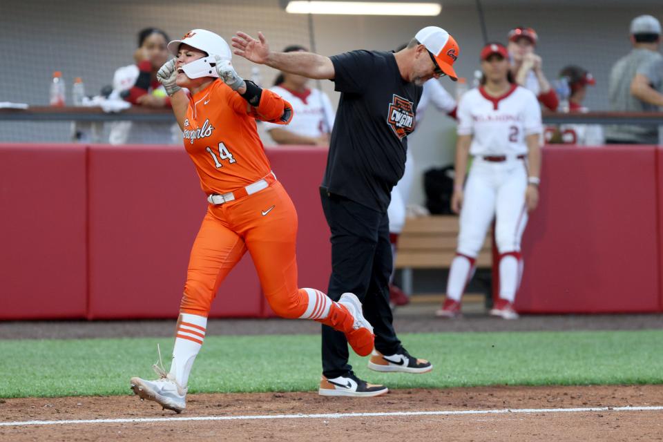 OSU infielder Karli Godwin (14) celebrates beside coach Kenny Gajewski after hitting a home run in the fifth inning of a 6-3 Bedlam win on May 3 in Norman.