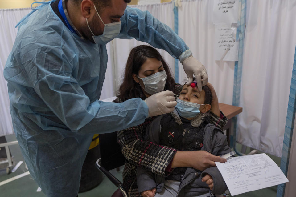 A health care worker takes a nasal swab sample from a Palestinian child in a COVID-19 testing center, in the West Bank city of Ramallah, Wednesday, Feb. 2, 2022. Palestinians are facing a winter coronavirus surge driven by the omicron variant, placing stress on the medical system even though vaccines are widely available. (AP Photo/Nasser Nasser)