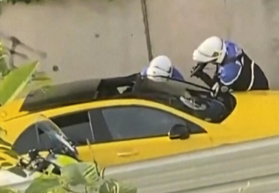 In this grab taken from video provided by @Ohana_FNG, two police officers question a driver, with one seen pointing a gun toward the window of a yellow car, in Nanterre, France, June 27, 2023.  / Credit: AP