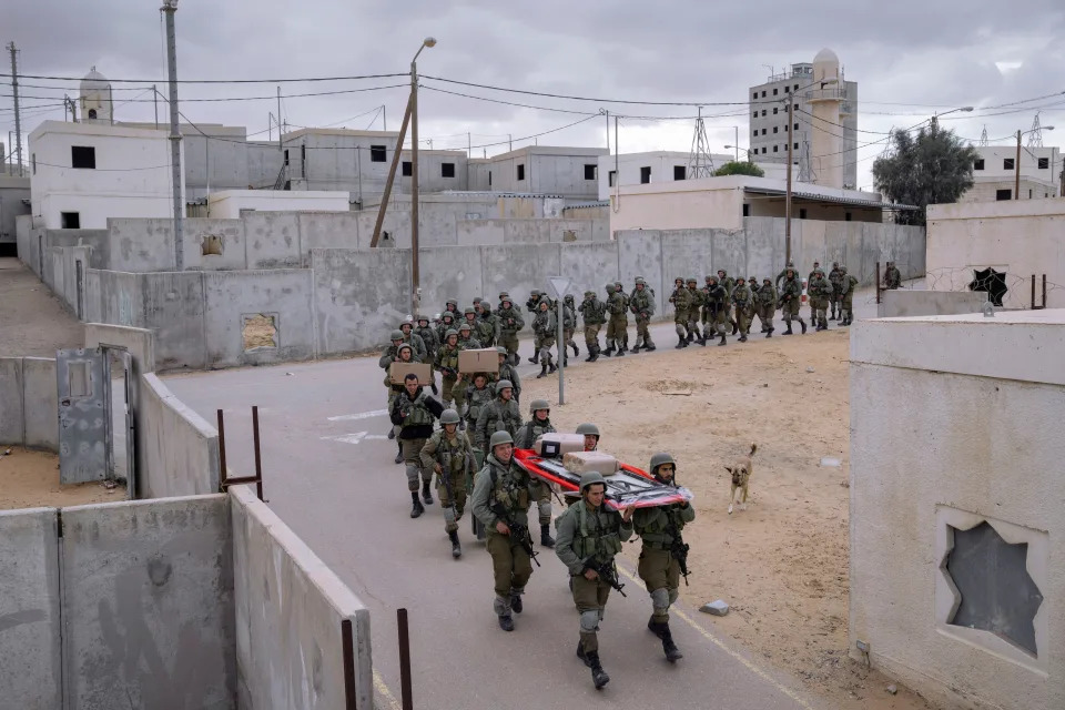 Israeli soldiers carry supplies at the end of an urban warfare exercise session at an army training facility at the Zeelim army base, southern Israel, Feb. 10, 2022.