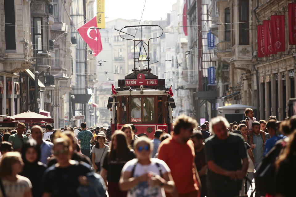 People walk in central Istanbul's Istiklal Avenue, the main shopping road of Istanbul, in this photo dated Wednesday, Aug. 22, 2018. Tourists have returned in droves to Turkey, helped this summer by the sharp fall in the value of the Turkish lira following economic uncertainty and a rift with the United States. (AP Photo/Mucahid Yapici)