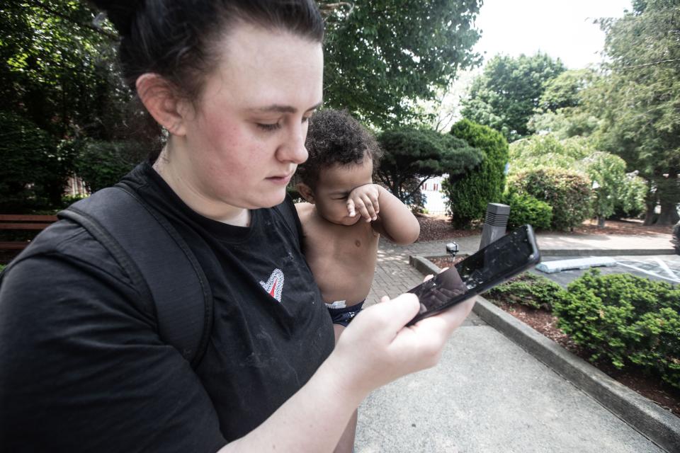 Savanna Harp, 24, holds her son Emir, 1, outside the Ramada hotel in Yonkers as she searches online for a new hotel May 15, 2023. Harp had been staying at the hotel with her son and boyfriend for the past week before being told they had to leave because asylum seekers from New York City would be using the rooms at the hotel. Harp lost her home in Mamaroneck due to flooding caused by Hurricane Ida and has been living in various hotels ever since.