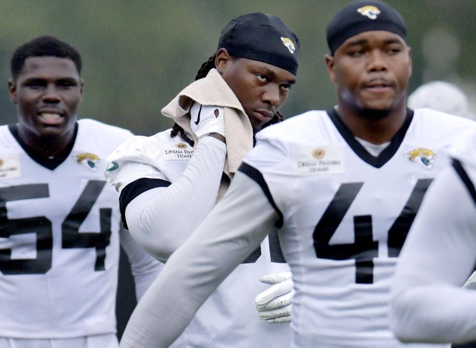 Jaguars defensive end Jordan Smith (center) wipes off the sweat while teammates D.J. Coleman (54) and Travon Walker (44) stretch before Friday's practice at the Miller Electric Center.
