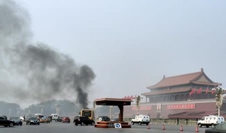 Vehicles travel along Chang'an Avenue as smoke raises in front of a portrait of late Chinese Chairman Mao Zedong at Tiananmen Square in Beijing October 28, 2013. REUTERS/Staff
