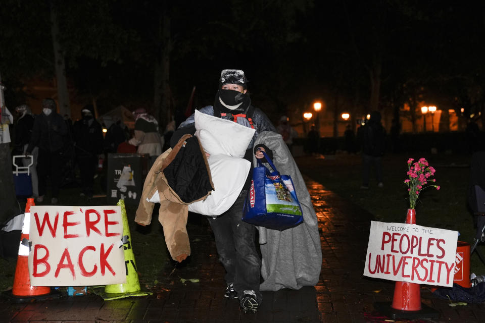 People carry belongings out of an encampment set up by pro-Palestinian demonstrators after police arrived for a raid on the campus at the University of Southern California Sunday, May 5, 2024, in Los Angeles. (AP Photo/Ryan Sun)