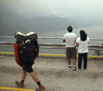 <p>A hiker and two others look at smoke from the Eagle Creek wildfire on the Oregon side of the Columbia River Gorge from the Bridge of the Gods, spanning the Columbia River between Washington and Oregon states, near Stevenson, Wash., on Sept. 6, 2017. (Photo: Randy L. Rasmussen/AP) </p>