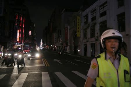 A police stands in front of a building during a massive power outage in Taipei, Taiwan August 15, 2017. REUTERS/Stringer