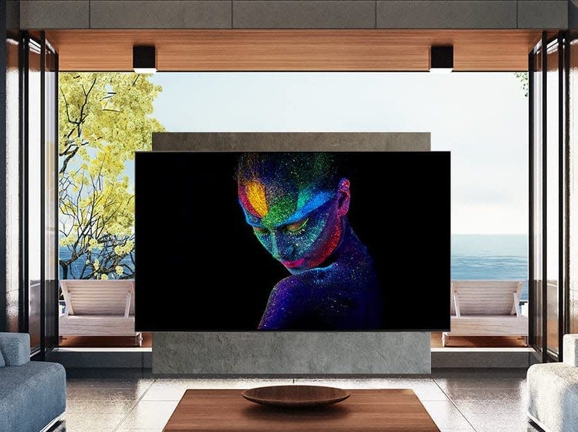 samsung 65 inch class oled 4k series quantum hdr smart tv displaying a woman with rainbow makeup in a living room