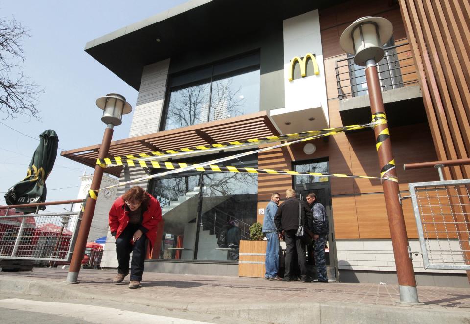 A woman makes her way under a barrier tape outside a McDonald's restaurant, which was earlier closed for clients, in the Crimean city of Simferopol April 4, 2014. McDonald's has suspended work at its restaurants in Crimea for "manufacturing reasons", the U.S. fast food chain said on Friday, the second international company to cease operations this week on the peninsula annexed by Russia. REUTERS/Stringer (UKRAINE - Tags: POLITICS BUSINESS SOCIETY)