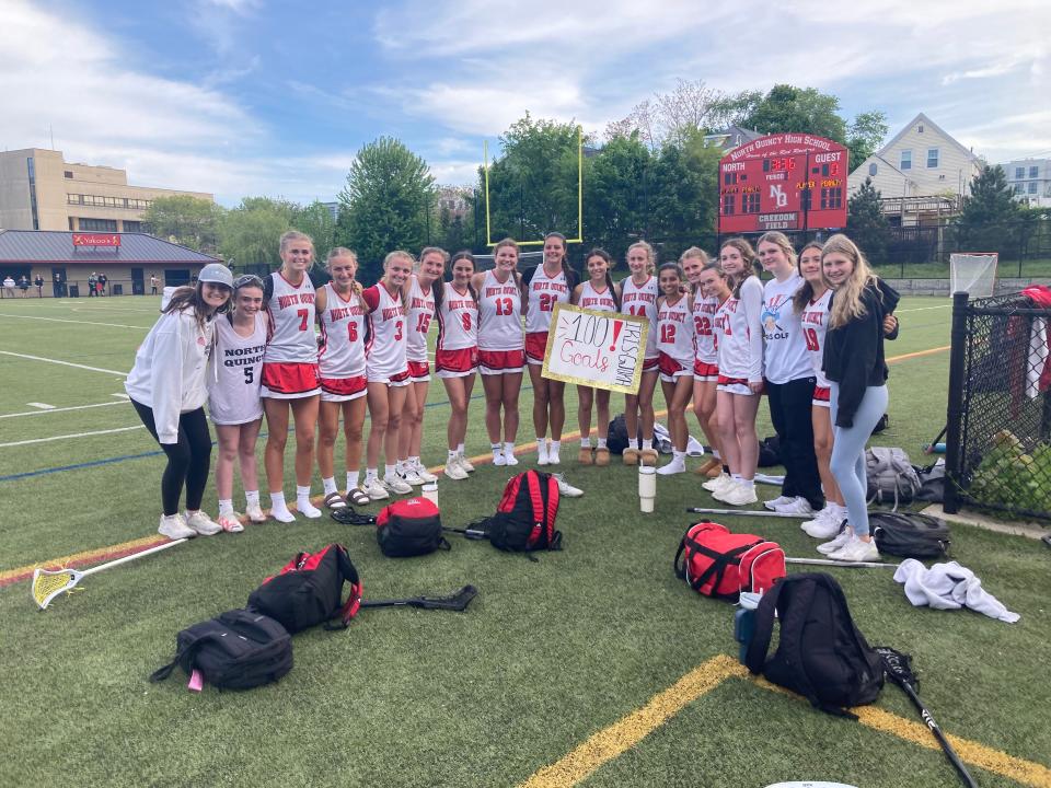 Members of the North Quincy High girls lacrosse team pose with junior Iris Gjoka (center, holding sign) after a 16-11 win over Stoughton at Creedon Field on Monday, May 20, 2024. Gjoka scored 9 goals, including No. 100 for her career.