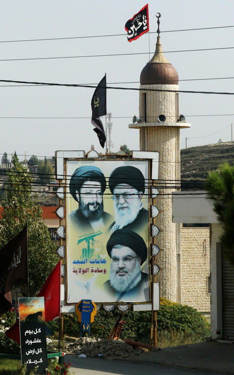 Portraits of Iranian-born Lebanese cleric Musa al-Sadr (top L), Iran's Supreme Leader Ayatollah Ali Khamenei (top R) and Hizbollah leader Hasan Nasrallah outside a mosque in Lebanon - Credit:  MAHMOUD ZAYYAT/AFP