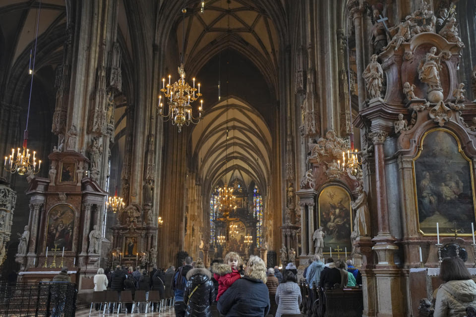 A woman holds a child while attending mass at the St. Stephen's Cathedral in Vienna, Austria, Sunday, Nov. 21, 2021. The Austrian government announced a nationwide lockdown that will start Monday and comes as average daily deaths have tripled in recent weeks and hospitals in heavily hit states have warned that intensive care units are reaching capacity.(AP Photo/Vadim Ghirda)