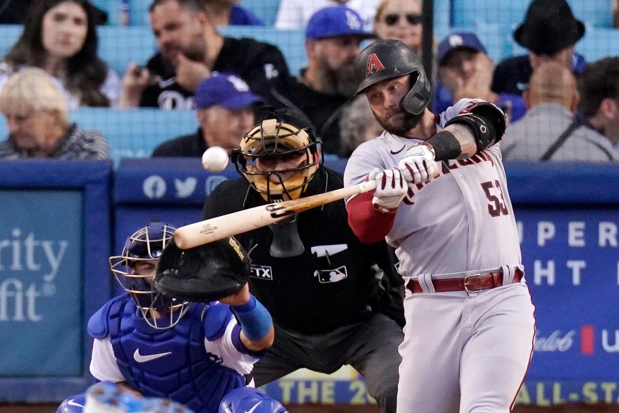 Arizona Diamondbacks' Christian Walker, right, hits a solo home run as Los Angeles Dodgers catcher Austin Barnes, left, and home plate umpire Larry Vanover watch during the second inning of a baseball game Monday, May 16, 2022, in Los Angeles. (AP Photo/Mark J. Terrill)