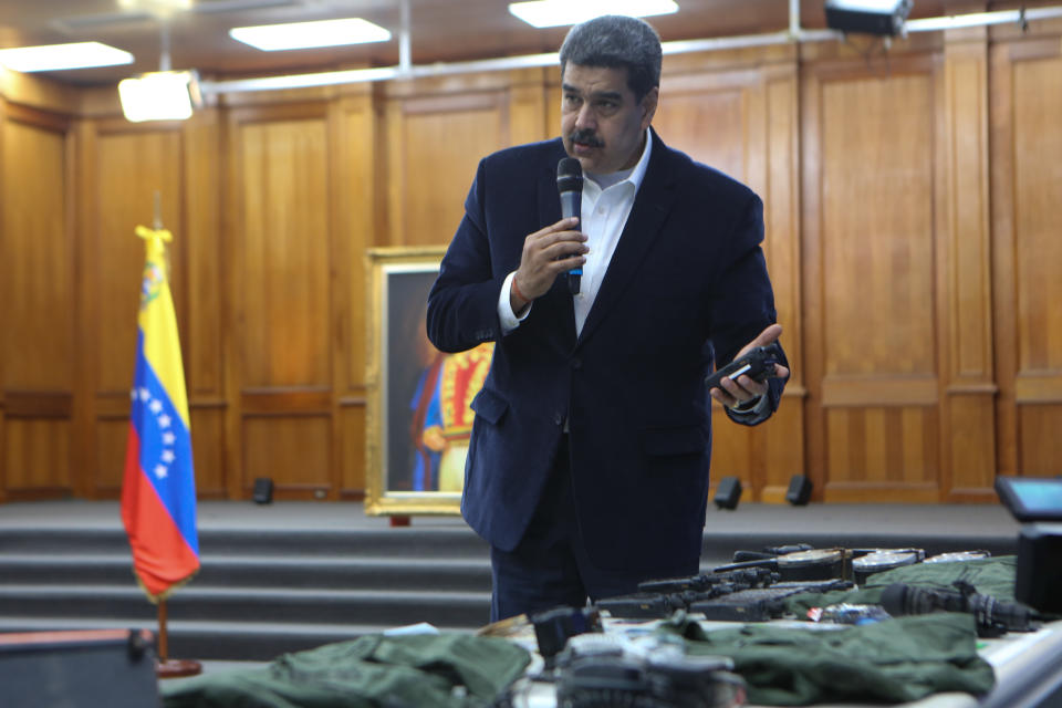 FILE- This photo released by the Venezuelan Miraflores presidential press office shows President Nicolas Maduro speaking over military equipment that he says was seized during an incursion into Venezuela, during his televised address from Miraflores in Caracas, Venezuela, May 4, 2020. Maduro said authorities arrested two U.S. citizens among a group of "mercenaries" the day after a beach raid purportedly aimed at capturing Maduro. (Miraflores press office via AP, File)