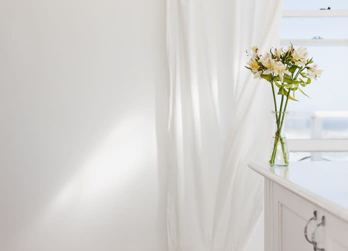 Vase of flowers on desk in white room