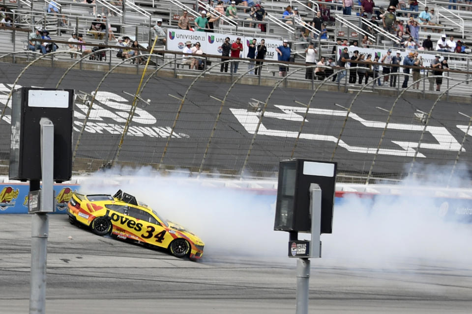 Fans look on as Michael McDowell (34) crashes in Turn 4 during a NASCAR Cup Series auto race at Texas Motor Speedway in Fort Worth, Texas, Sunday, April 14, 2024. (AP Photo/Randy Holt)