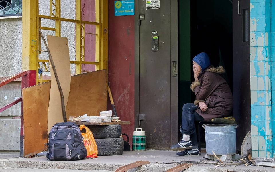 A woman sits at the entrance of her apartment building, which was damaged in Kharkiv. The residents no longer access to electricity, gas or water indoors