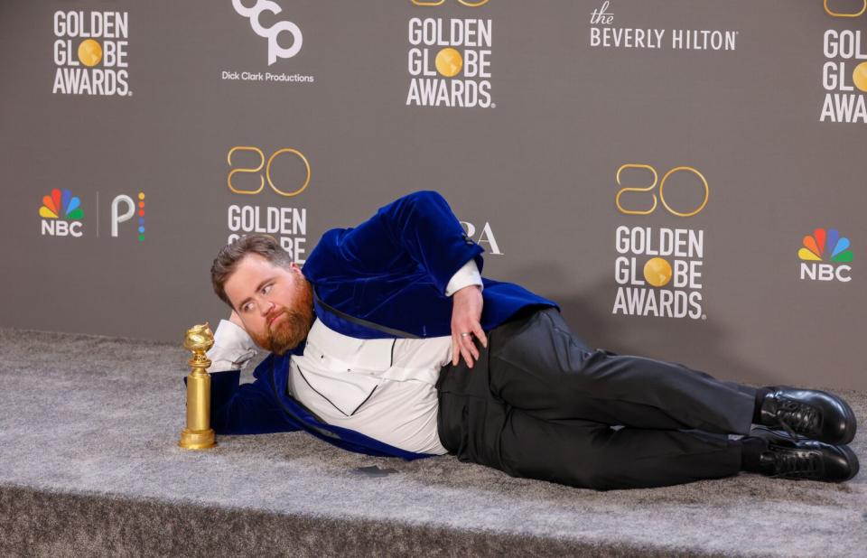 A man lays down with his Golden Globe award