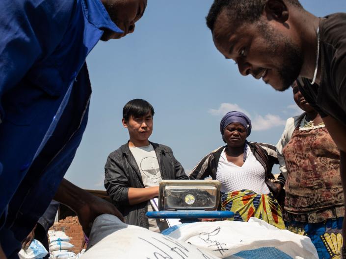 A man from China watches workers weigh sacks of cobalt