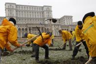 Greenpeace activists dig into the yard of Romania's Parliament, to protest against a Canadian company's plan to set up Europe's biggest open-cast gold mine in Romania, in Bucharest December 9, 2013. A special Romanian parliament commission overwhelmingly rejected a draft bill that would have allowed Canada's Gabriel Resources to set up Europe's biggest open-cast gold mine in the small Carpathian town of Rosia Montana last month. However, parliament plans to revise a mining law that could open way for the project. REUTERS/Bogdan Cristel (ROMANIA - Tags: ENVIRONMENT SOCIETY CIVIL UNREST BUSINESS POLITICS)